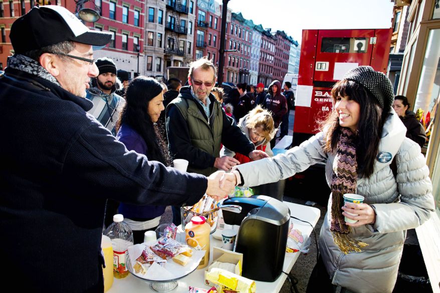 Felice Vazquez, 40, of Hoboken, greets a neighbor as she mans a table providing hot drinks and snacks on Washington Street as the buildings around them remain without power due to damage caused by Superstorm Sandy, Sunday, Nov. 4, 2012, in Hoboken, New Jersey. (AP Photo/ John Minchillo)
