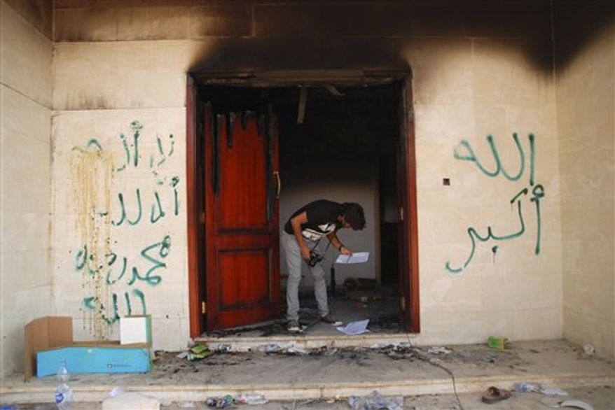 ** FILE ** In this Wednesday, Sept. 12, 2012 photo, a man looks at documents at the U.S. consulate in Benghazi, Libya, after an attack that killed four Americans, including Ambassador Chris Stevens. The graffiti reads, "no God but God," " God is great," and "Muhammad is the Prophet." (AP Photo/Ibrahim Alaguri)