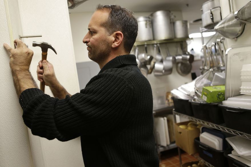 **FILE** Anthony Cavallo, owner of the restaurant Vintage 50, mounts a potato cutter in his restaurant in Leesburg, Va., on Oct. 8, 2012. (Associated Press)