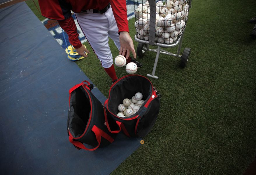 A member of the Washington Nationals drops baseballs into a bag before Game 3 of the National League division baseball series against the St. Louis Cardinals on Wednesday, Oct. 10, 2012, in Washington. (AP Photo/Pablo Martinez Monsivais)