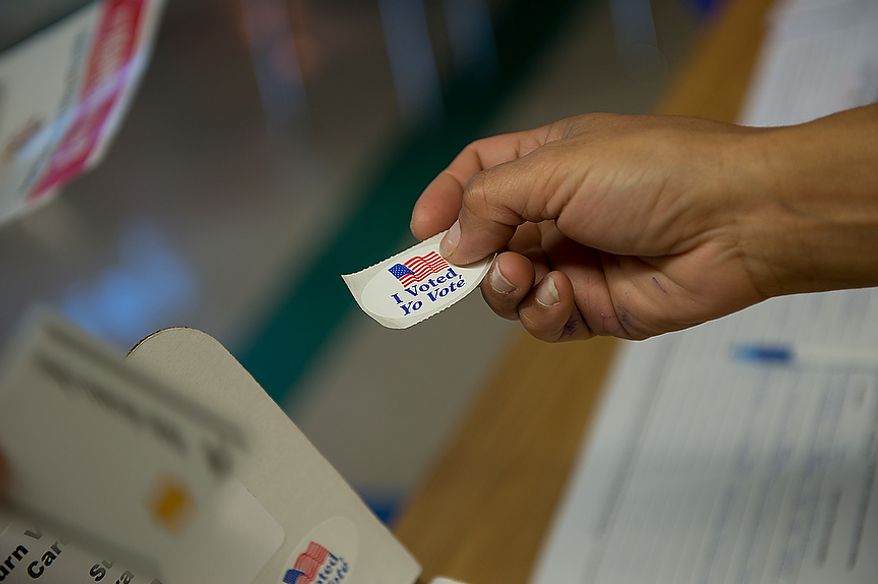 Elections operation judge Rosario Khan hands out "I voted" stickers on Election Day at Winston Churchill High School in Potomac, Md., on Nov. 6, 2012. (Barbara L. Salisbury/The Washington Times)