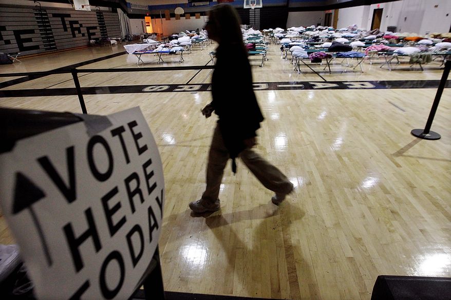 A person walks through a makeshift shelter in a gymnasium at Toms River East High School on the way to vote on Tuesday, Nov. 6, 2012, in Toms River, N.J. Voter turnout was heavy in several storm-ravaged Jersey shore towns, with many voters expressing relief and even elation at being able to vote at all, considering the devastation. (AP Photo/Mel Evans)