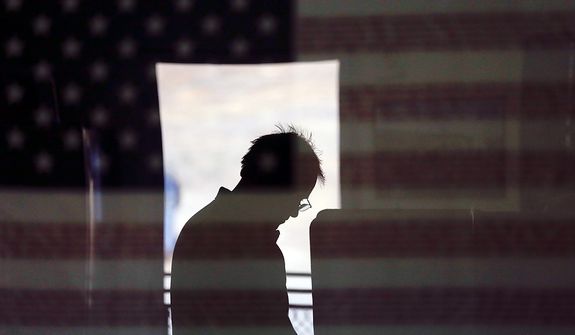 Hal Pigg casts his vote, reflected in an image of a flag, on Election Day Tuesday, Nov. 6, 2012, in Jamul, Calif. (AP Photo/Gregory Bull)