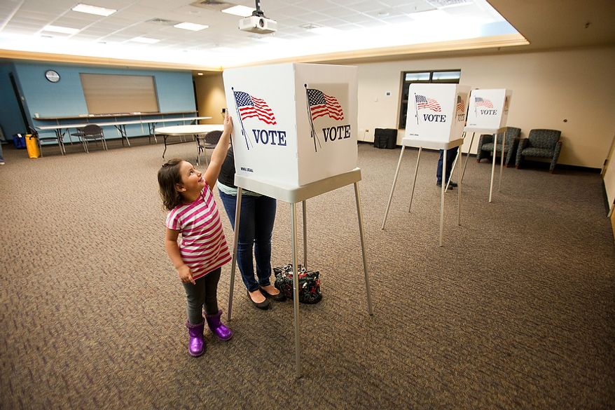 Baylee Hernandez, 4, plays next to her mother Britni Tortora, of Arvada, while she votes at the Apex Center Tuesday Nov. 6, 2012 in Arvada, Colo. (AP Photo/Barry Gutierrez)