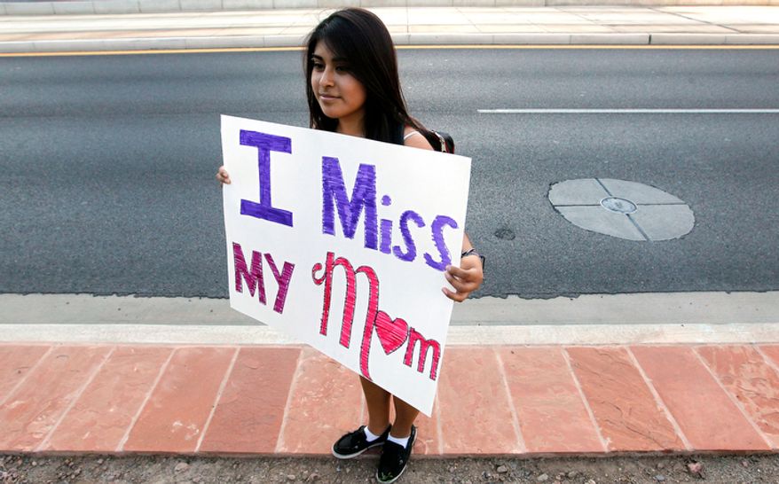 **FILE** Cynthia Diaz, 17, quietly holds up a sign Sept. 19, 2012, dedicated to her mother as she joins dozens who rally in front of U.S. Immigration and Customs Enforcement building, a day after a portion of Arizona's immigration law took effect in Phoenix. Her mother was deported the previous year. Civil rights activists contend the state's law will lead to systematic racial profiling, as the protesters chanted "No papers, no fear." (Associated Press)