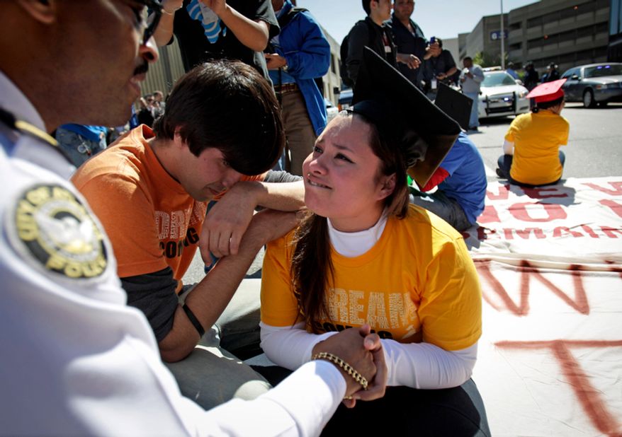 **FILE** Illegal immigrant Viridiana Martinez (right) is comforted April 5, 2011, by activist Mohammad Abdollahi as Maj. K.E. Williams (left) of the Atlanta Police Department warns her of arrest unless she moves during a protest for rights for higher education for illegal immigrants in Atlanta. (Associated Press)