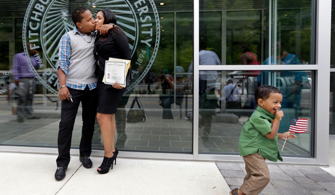 **FILE** New U.S. citizen Johanna Cornielle Mesa of Lawrence, Mass., originally from the Dominican Republic, gets a kiss from her boyfriend, Luis, while their son Luis Jr. plays with a flag after a naturalization ceremony in Fitchburg, Mass., on Sept. 6, 2012. (Associated Press)