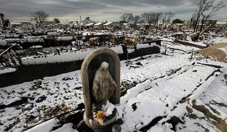 ** FILE ** A religious statue stands in the fire-scorched landscape of Breezy Point after a Nor&#x27;easter snowstorm on Nov. 8, 2012, in New York. The beachfront neighborhood was devastated during Superstorm Sandy when a fire pushed by the raging winds destroyed many homes. (Associated Press)