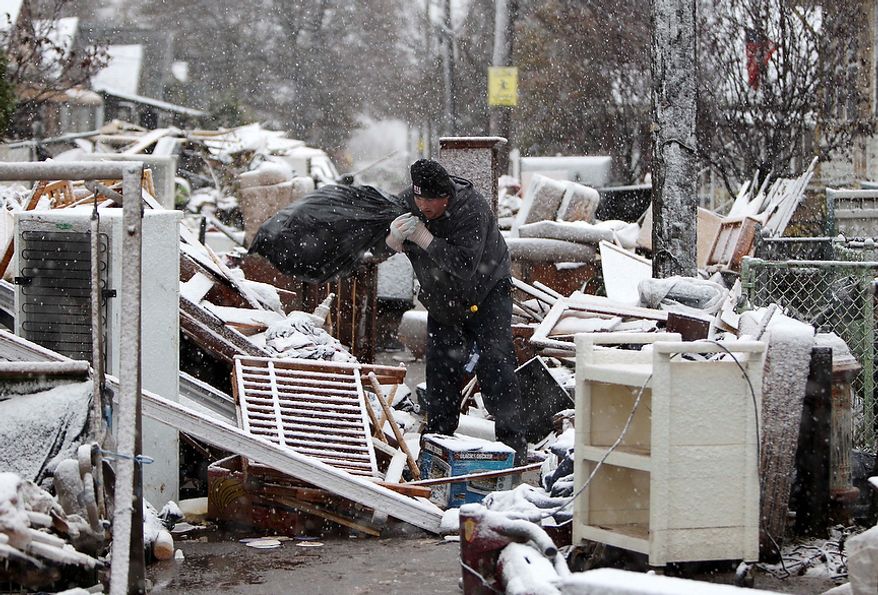 Jason Auer works in the snow cleaning a relatives house in the New Dorp section of Staten Island, New York, Wednesday, Nov. 7, 2012. (AP Photo/Seth Wenig)