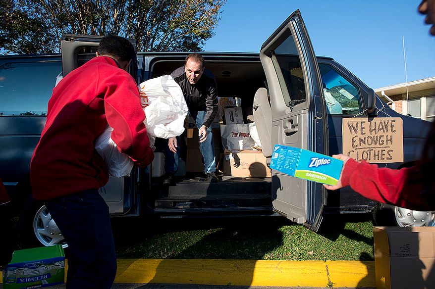 Mike Trigiani (center), a parishioner at St. Andrew the Apostle Catholic Church in Silver Spring, Md., loads donated items into a passenger van outside the church on Nov. 9, 2012. The van, which was filled with food, clothes, toiletries, cleaning supplies and baby products, will be driven to St. Benedict Church in Holmdel, N.J., where the supplies will be distributed to victims of Superstorm Sandy. (Barbara L. Salisbury/The Washington Times)