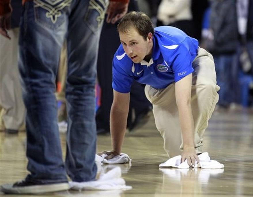 Workers try to dry the basketball court before the second half of the Navy-Marine Corps Classic NCAA college basketball game between Florida and Georgetown aboard the USS Bataan at the Mayport Naval Station, Friday, Nov. 9, 2012, in Jacksonville, Fla. The game was canceled due to condensation on the court. (AP Photo/John Raoux)
