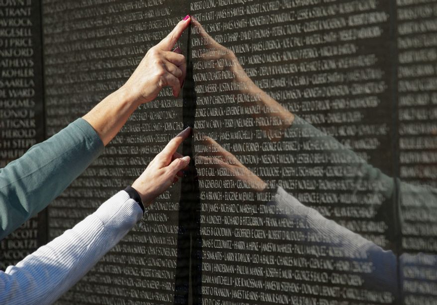 People point to names on the Vietnam Veterans Memorial on Veterans Day, Sunday, Nov. 11, 2012, in Washington. (Rod Lamkey Jr./The Washington Times)