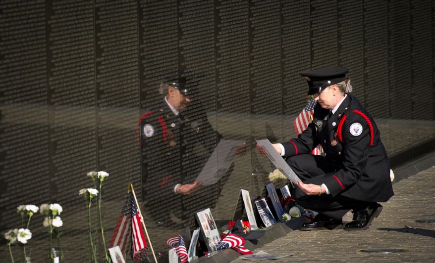 Susan D. Wiseman, of Fayetteville, Ga., looks at a photo of her cousin US Army Specialist Fourth Class Guy Mears, 20, who was killed in action while trying to rescue men in a downed helicopter he was on as a crew member in Vietnam on Oct. 17. 1970, while attending an event at the Vietnam Veterans Memorial during Veteran's Day weekend in Washington, D.C., Sunday, Nov. 11, 2012. (Rod Lamkey Jr./The Washington Times)