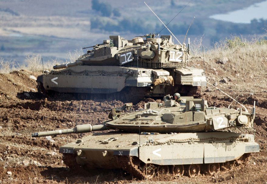 Shells fired by the Syrian army explode in the Syrian village of Bariqa (top) on Monday. Israeli tanks (above) get into firing position in the Israeli-controlled Golan Heights overlooking the Syrian village. Israel said it responded to stray mortar fire from Syria. Israel has promised a tough response if the fire continues. (Associated Press)