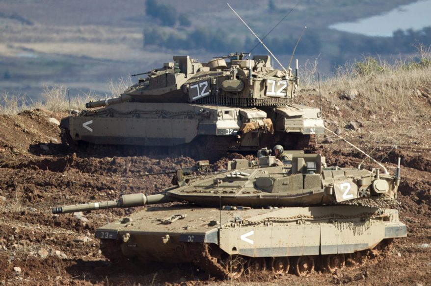 ** FILE ** Israeli tanks in the Israeli-controlled Golan Heights overlook the Syrian village of Bariqa on Nov. 12, 2012. The Israeli military says "Syrian mobile artillery" was hit after the Israelis responded to stray mortar fire from its northern neighbor. The incident marked the second straight day that Israel has responded to fire from Syria that does not appear to be aimed at Israeli targets; nonetheless, Israel has promised a tough response if the fire continues. (Associated Press)