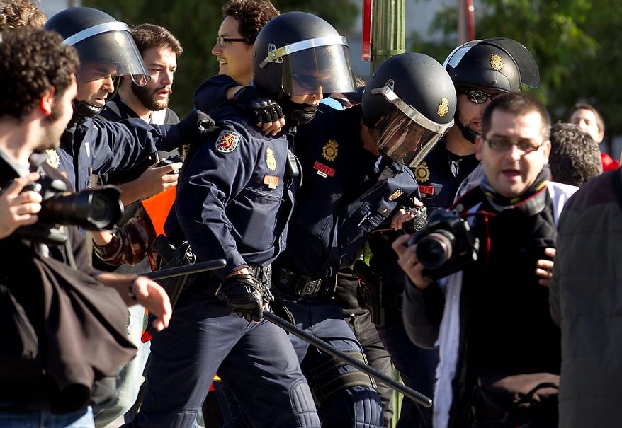 A police officer, center right, is helped by a colleague after getting hurt during a general strike in Madrid, Wednesday Nov. 14, 2012. A Spanish Interior Ministry official says 32 people have been arrested and 15 people treated for minor injuries in disturbances as a general strike in Spain against austerity measures and economic reforms began. The General Workers Union said the nationwide stoppage, the second this year, was being heeded by nearly 100 percent of workers Wednesday in the automobile, energy, shipbuilding and constructions industries. (AP Photo/Paul White)