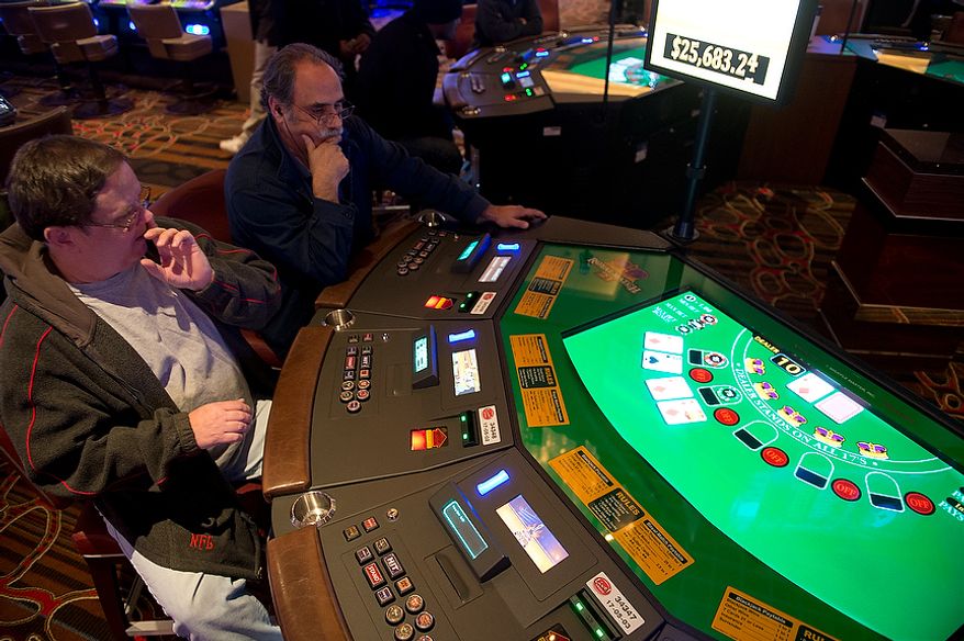 Merle Miller, left, of Clinton, Md. and Pablo (who did not give his last name) of Silver Spring, Md. play an electronic table version of Black Jack at Maryland Live! Casino in Hanover, Md. on Wednesday, Nov. 14, 2012. The casino announced today in a press conference that it will be adding live table games, so many of these electronic versions will be replaced, hopefully by spring. "You just hope you get a good dealer who gets into it," says Miller, who says he plays Black Jack everywhere and is excited about the prospect of playing with a live dealer. "It's fun," he says. (Barbara L. Salisbury/The Washington Times)
