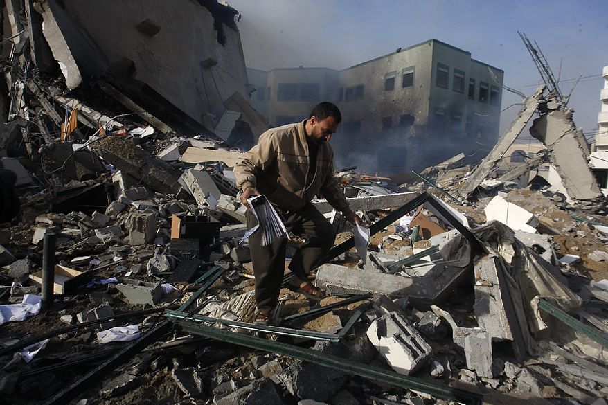 A Palestinian man picks up a binder from the debris after an Israeli air strike on the building of Hamas' Ministry of Interior in Gaza City, Friday, Nov. 16, 2012. (AP Photo/Hatem Moussa)