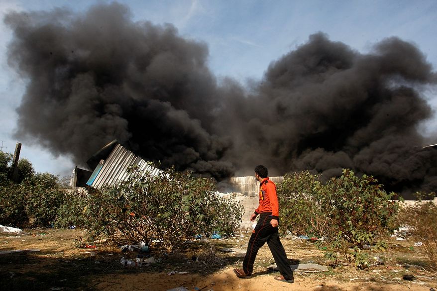 A Palestinian man walks past a fire after an Israeli airstrike on a wood factory in east Jabaliya, north Gaza, Friday, Nov. 16, 2012. Israel offered to suspend its offensive in the Gaza Strip on Friday during a brief visit by Egypt's premier there if militants refrain from firing rockets at Israel, an official said, but the Palestinians unleashed a fresh salvo. (AP Photo/Hatem Moussa)
