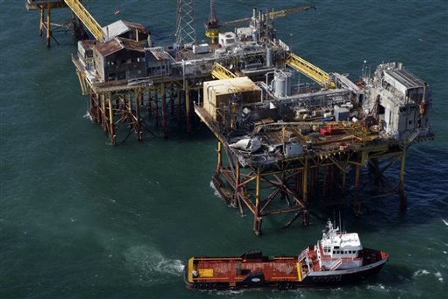 In this aerial photograph, a supply vessel moves near an oil rig damaged by an explosion and fire, Friday, Nov. 16, 2012, in the Gulf of Mexico about 25 miles southeast of Grand Isle, La. Four people were transported to a hospital with critical burns and two were missing. (AP Photo/Gerald Herbert)