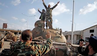 Opposition fighters celebrate capturing a tank after storming a military base in Aleppo, Syria, on Monday. Islamist rebels refuse to join a Western-backed coalition. (Associated Press)

