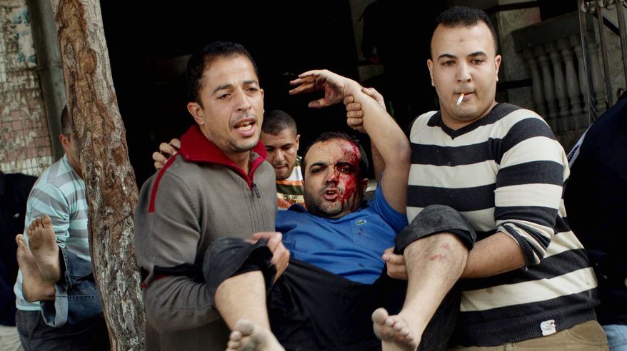 Palestinians carry the injured after an Israeli strike on a building in Gaza City on Monday. It was the second strike on the building in two days. (Associated Press)
