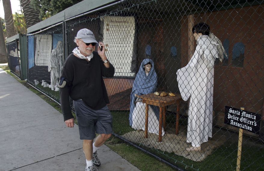 **FILE** A man walks past two of the traditional Nativity scenes along Ocean Avenue at Palisades Park in Santa Monica, Calif., on Dec. 13, 2011. (Associated Press)
