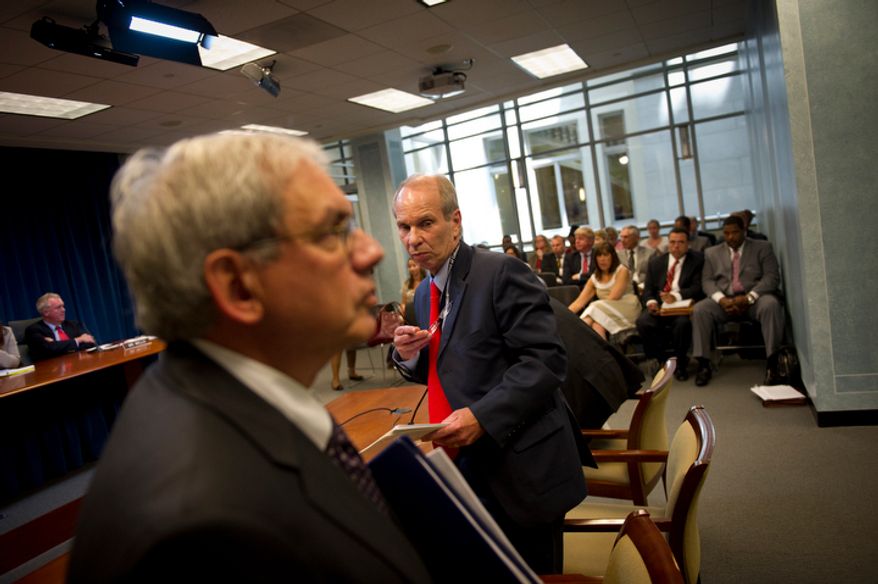 **FILE** Buddy Roogow (right), D.C. Lottery Executive Director, and Irvin B. Nathan, D.C. Attorney General, make their exit June 29, 2011, following their testimony at the Wilson Building in Washington, D.C., before a city council hearing regarding online poker in D.C. (Rod Lamkey Jr./The Washington Times)
