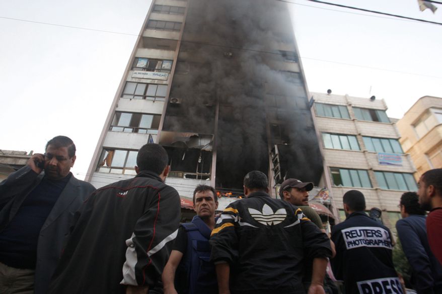 People stand in front of a high rise housing media organizations in Gaza City, Monday, Nov. 19, 2012. Israeli military struck the building for the second time in two days. The Hamas TV station, Al Aqsa, is located on the top floor. (AP Photo/Hatem Moussa)