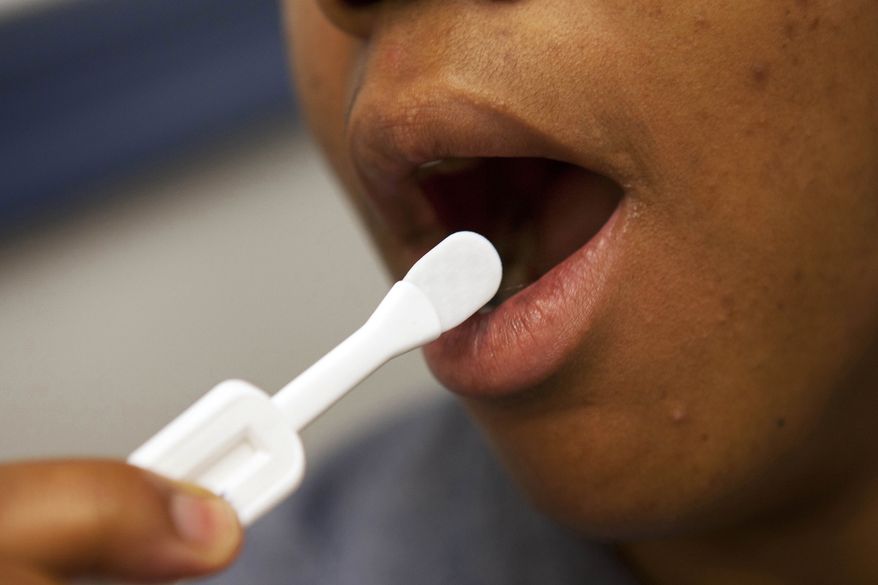 FILE - This June 27, 2012 file photo shows a patient using an oral test for HIV, inside the HIV Testing Room at the Penn Branch of the District of Columbia Department of Motor Vehicles, in southeast Washington. (AP Photo/Jacquelyn Martin, File)