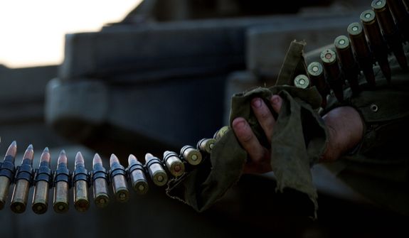 An Israeli soldier cleans ammunition as he sits on top of a tank in a staging area near the Gaza border in southern Israel on Nov. 20, 2012. Israeli aircraft battered the headquarters of the Islamic National Bank, which Gaza&#39;s Hamas leaders set up to sidestep international sanctions on their rule. (Associated Press)