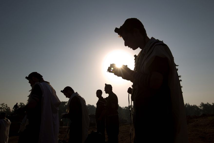 Israeli soldiers read from a holy book as they pray in a staging area near the Gaza border in southern Israel on Nov. 20, 2012. Israeli aircraft battered the headquarters of the Islamic National Bank, which Gaza's Hamas leaders set up to sidestep international sanctions on their rule. (Associated Press)