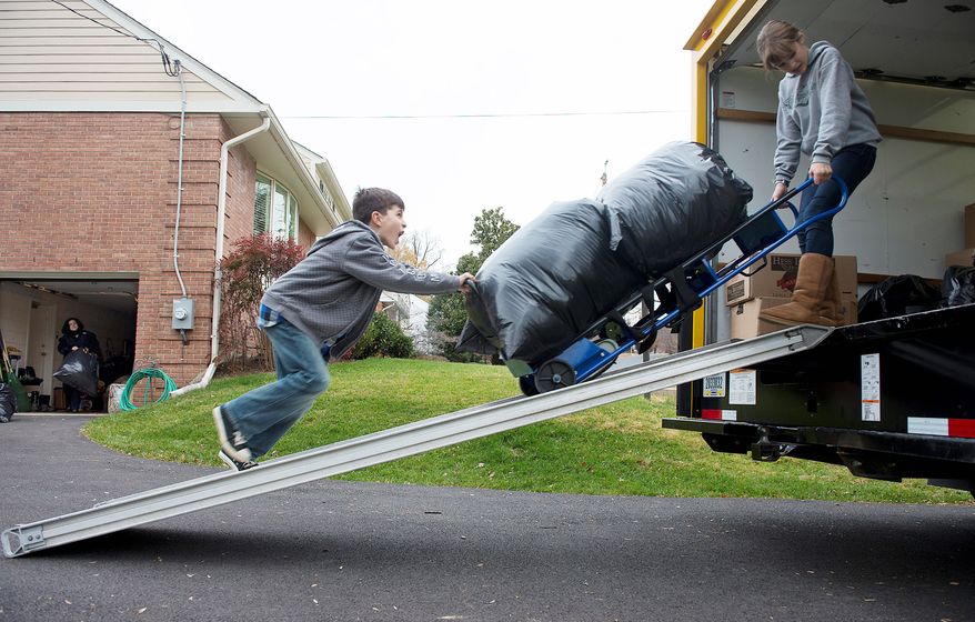 Andrew Audas, 9, and his sister Abbi, 12, of Bethesda, roll a dolly carrying bags full of donated clothes up the ramp into their 12-foot rental truck, which they filled before heading north Wednesday to help families who lost almost everything they had during Superstorm Sandy on the New Jersey shore. (Barbara L. Salisbury/The Washington Times)