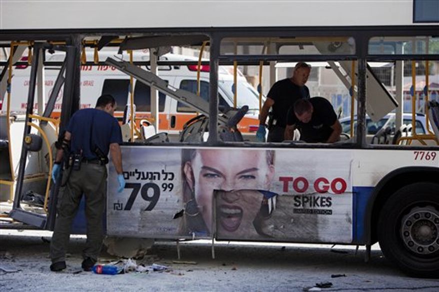Israeli police officers examine a blown-up bus at the site of a bombing in Tel Aviv, Israel, Wednesday, Nov. 21, 2012. (AP Photo/Oded Balilty)