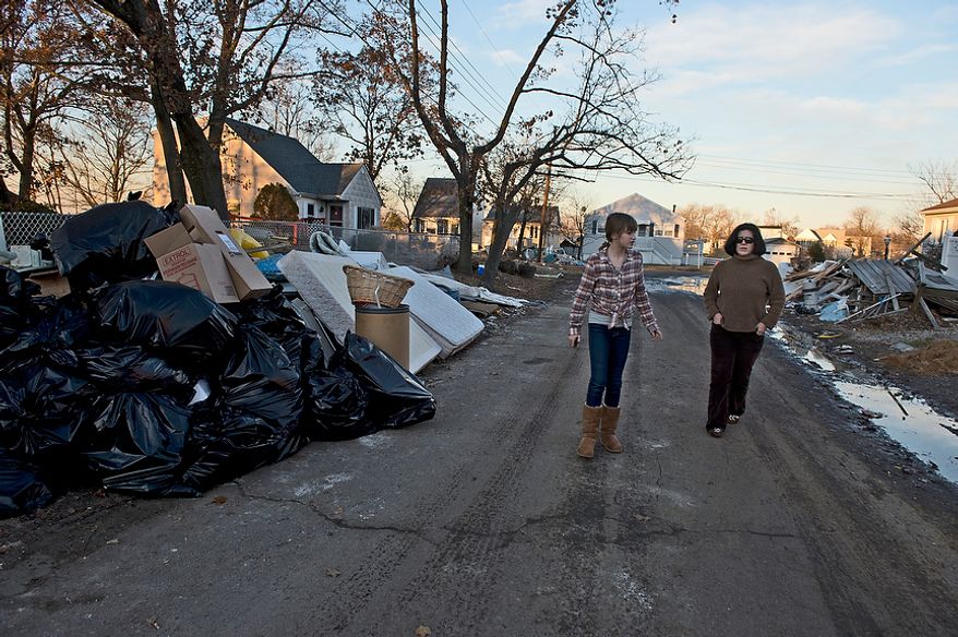 Abbi and Tiffany walk down a street in Union Beach, N.J. where people have emptied all of their belongings into the street after Hurricane Sandy on Wednesday, Nov. 21, 2012. They have donated items here that they collected in Project Keep Them Cozy, which Abbi, 12, and Andrew, 9, spearheaded. The family is spending their Thanksgiving up here volunteering. (Barbara L. Salisbury/The Washington Times)