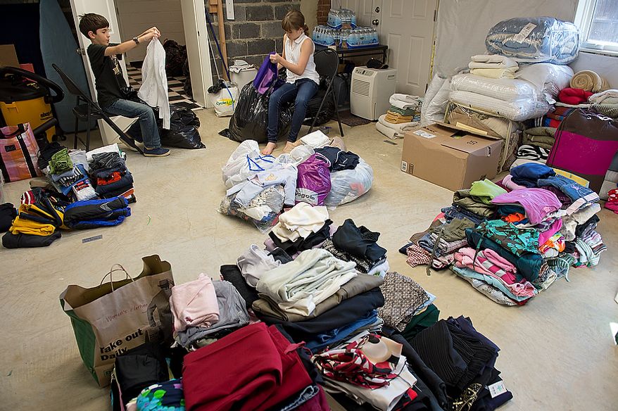 Andrew Audas, left, 9, and his sister Abbi, 12, go through bags of donated clothing in the basement of their Bethesda, Md. home on Tuesday, Nov. 13, 2012. The two children were struck by the devastating effect of Hurricane Sandy and told their parents they wanted to do something to help. So they started "Project Keep Them Cozy" to collect coats, hats, gloves and scarves for those who lost everything in the storm. The family will drive all of the donated items up to New Jersey, where they plan to spend their Thanksgiving volunteering to help Sandy victims. (Barbara L. Salisbury/The Washington Times)