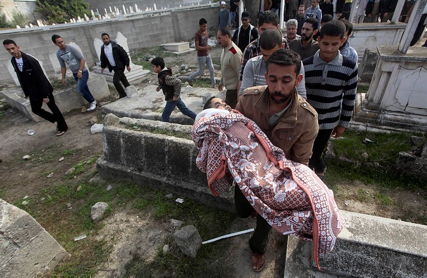 A Palestinian man carries the body of Mohammed Ashour, 10, killed the previous day in an Israeli air strike on Gaza City, during his funeral, Wednesday, Nov. 21, 2012. Israeli aircraft pounded Gaza with at least 30 strikes overnight, hitting government ministries, smuggling tunnels, a banker's empty villa and a Hamas-linked media office. (AP Photo/Ashraf Amra)