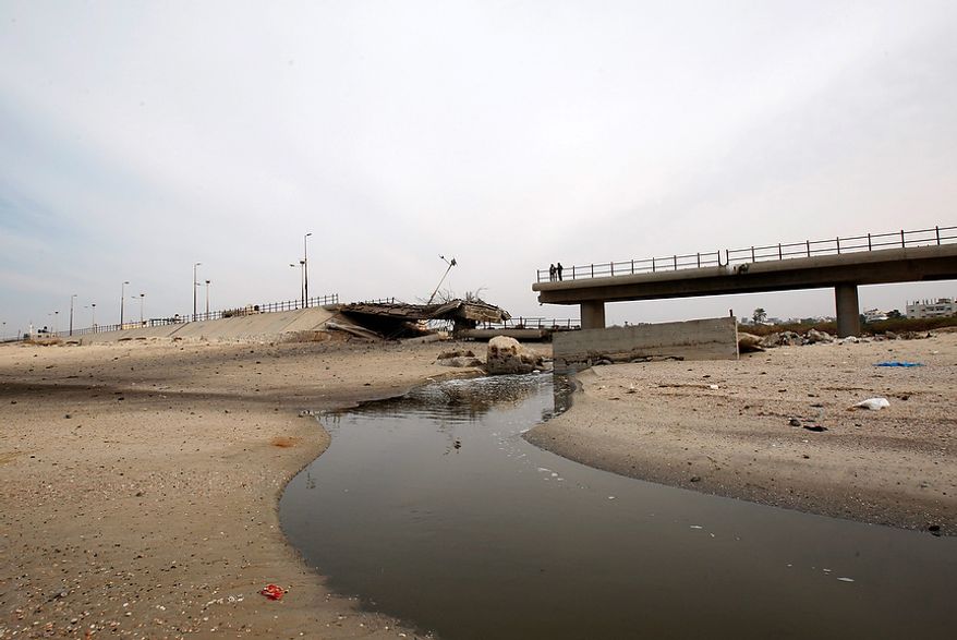 Palestinians look a destroyed beach bridge hit overnight in an Israeli air strike on the main beach road in Nuseirat, central Gaza Strip, Wednesday, Nov. 21, 2012. Israeli aircraft pounded Gaza with at least 30 strikes overnight, hitting government ministries, smuggling tunnels, a banker's empty villa and a Hamas-linked media office.(AP Photo/Adel Hana)