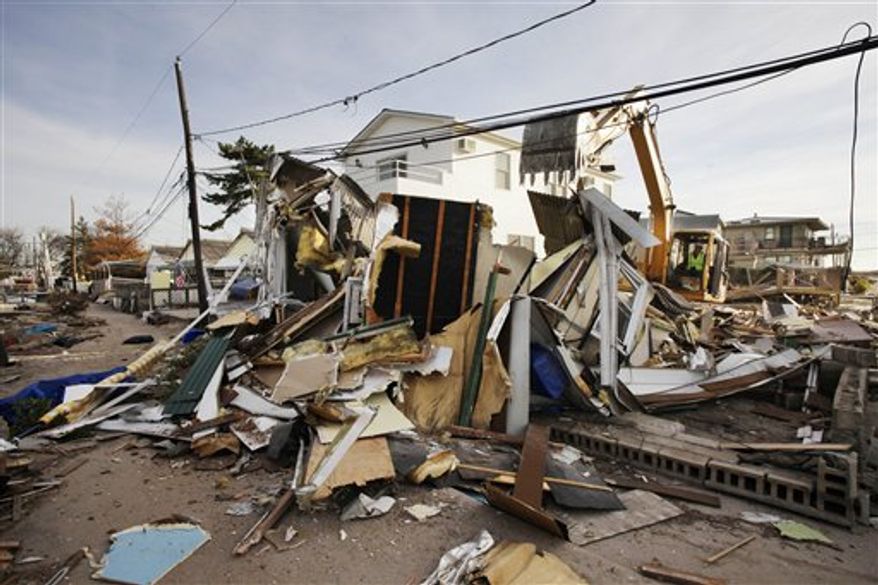 Backhoe operator Keith Henry levels a storm-damaged home in the Breezy Point section of the Queens borough of New York, Tuesday, Nov. 20, 2012. (AP Photo/Mark Lennihan)