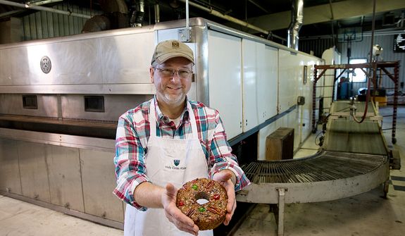 Ernie Polanskas, bakery manager at the Holy Cross Abbey bakery in Berryville, Va., holds one of the famous fruitcakes made by the monks in front of the huge industrial-sized oven that they bought back in the 1960s to bake bread. The monks bake from January to September, making about 10,000 fruitcakes, which they ship all over the world, primarily during the holiday season. The proceeds from the sales go to support the day-to-day operations of the monastery. This image was made Tuesday, Nov. 13, 2012. (Barbara L. Salisbury/The Washington Times)