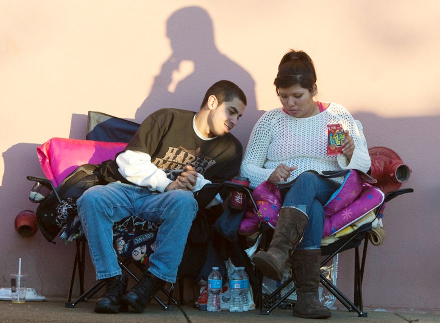 Jesus Marin, 19, from Alexandria, looks over deals with his girlfriend Mariela Paredes, 20, from Fairfax, while wait in line for Best Buy on Thanksgiving Day, Springfield, Va., Thursday, November 22, 2012. (Craig Bisacre/The Washington Times)