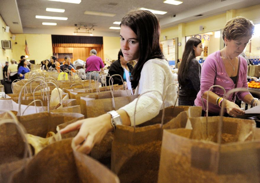 Michelle Devlin, center, checks the address on a bag containing a turkey dinner while her mother, Rebecca Devlin, right, dispatches volunteer drivers at St. Charles Church on New York's Staten Island, Thursday, Nov. 22, 2012. Volunteers served thousands of turkey dinners to people left homeless or struggling from Superstorm Sandy. (AP Photo/Stephanie Keith)