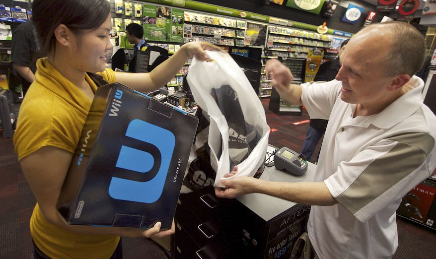 GameStop employee Lani Girran hands over a Wii U system to Kevin Owande, 51, of Renton, Wash., on a busy Black Friday at the GameStop Southcenter store in Seattle on Nov. 23, 2012. Owande was up early on Black Friday to purchase Wii U, one of the hottest products this holiday season. (Stephen Brashear/Invision for Nintendo/Associated Press)