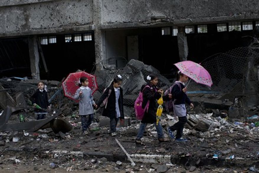Palestinian schoolchildren walk in debris by a damaged school in Gaza City, Saturday, Nov. 24, 2012. Schools in Gaza opened Saturday for the first time since the truce, which calls for an end to Gaza rocket fire on Israel and Israeli airstrikes on Gaza, came after eight days of cross-border fighting, the bloodiest between Israel and Hamas in four years. The school was damaged when Israeli forces struck on a nearby building. (AP Photo/Bernat Armangue)
