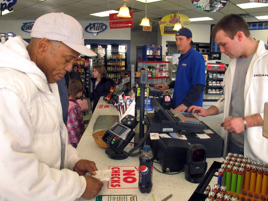 Michael Arrington (left) buys a Powerball ticket from cashier Lee Heilig (right) on Friday, Nov. 23, 2012, at a DeliMart convenience store in Iowa City, Iowa. (AP Photo/Grant Schulte)