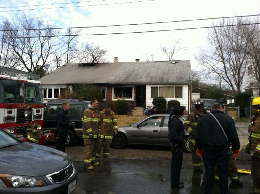 Prince George's County firefighters clean up after a Sunday morning duplex fire in Chillum that left three families homeless. (Meredith Somers/The Washington Times)
