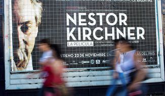 People walk by a banner promoting the documentary film &quot;Nestor Kirchner&quot; in Buenos Aires, Argentina, Wednesday, Nov. 21, 2012. The film hits the theaters on Thursday, the latest example of an ongoing effort to exalt the late president&#39;s memory, seeking to match the level of Juan Domingo Peron. Streets, hospitals, tunnels and even a soccer tournament is named after Nestor Kirchner, who served as president from 2003 to 2007 and died at the age of 60 on Oct. 27, 2010. (AP Photo/Natacha Pisarenko)