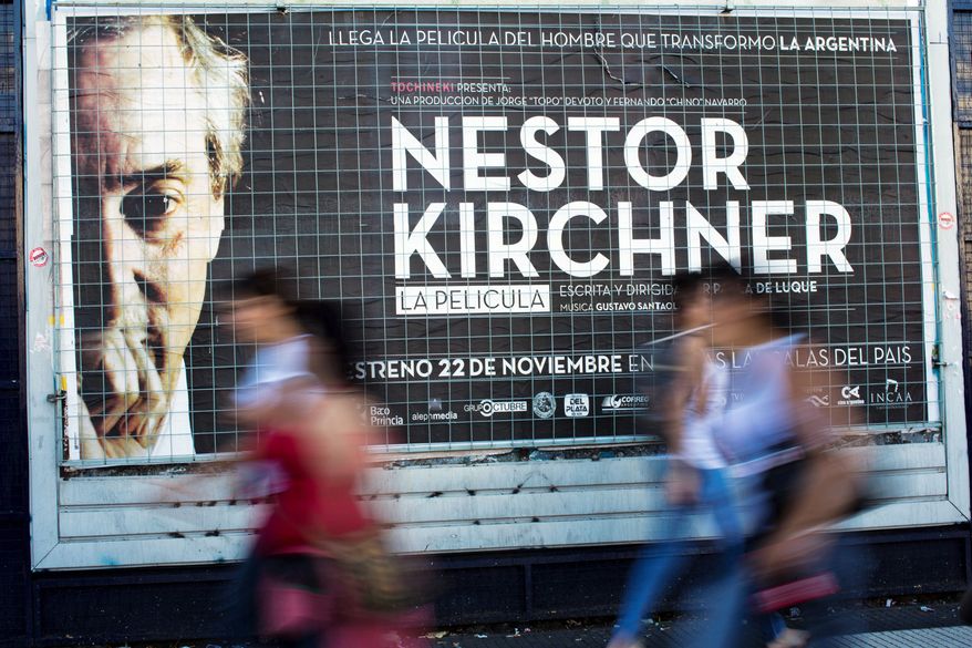 People walk by a banner promoting the documentary film "Nestor Kirchner" in Buenos Aires, Argentina, Wednesday, Nov. 21, 2012. The film hits the theaters on Thursday, the latest example of an ongoing effort to exalt the late president's memory, seeking to match the level of Juan Domingo Peron. Streets, hospitals, tunnels and even a soccer tournament is named after Nestor Kirchner, who served as president from 2003 to 2007 and died at the age of 60 on Oct. 27, 2010. (AP Photo/Natacha Pisarenko)