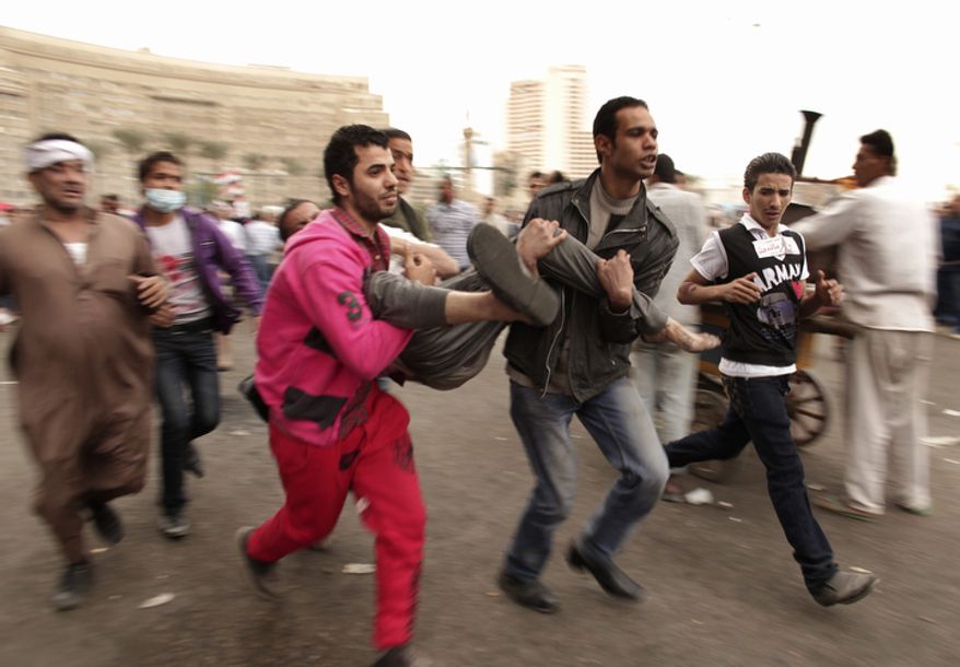 Protesters rush a wounded colleague to a field hospital in Tahrir Square on Friday, Nov. 23, 2012. Supporters and opponents of Egyptian Islamist President Mohammed Morsi staged rival rallies Friday after he assumed sweeping new powers, a clear show of the deepening polarization plaguing the country. In a Thursday, Nov. 22, 2012, decree, Mr. Morsi put himself above the judiciary and also exempted the Islamist-dominated constituent assembly writing Egypt's new constitution from judicial review. (AP Photo/Maya Alleruzzo)