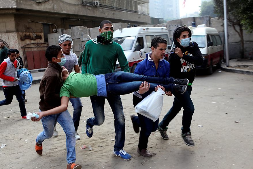 Egyptians carry a protester wounded in clashes with security forces near Tahrir Square, where an opposition rally has been called to voice rejection of President Mohammed Morsi's seizure of near-absolute powers, in Cairo on Tuesday, Nov. 27, 2012. The Health Ministry said about 444 people have been wounded nationwide, including 49 who remain hospitalized, since the clashes erupted on Friday, according to a statement carried by the official news agency, MENA. (AP Photo/Thomas Hartwell)